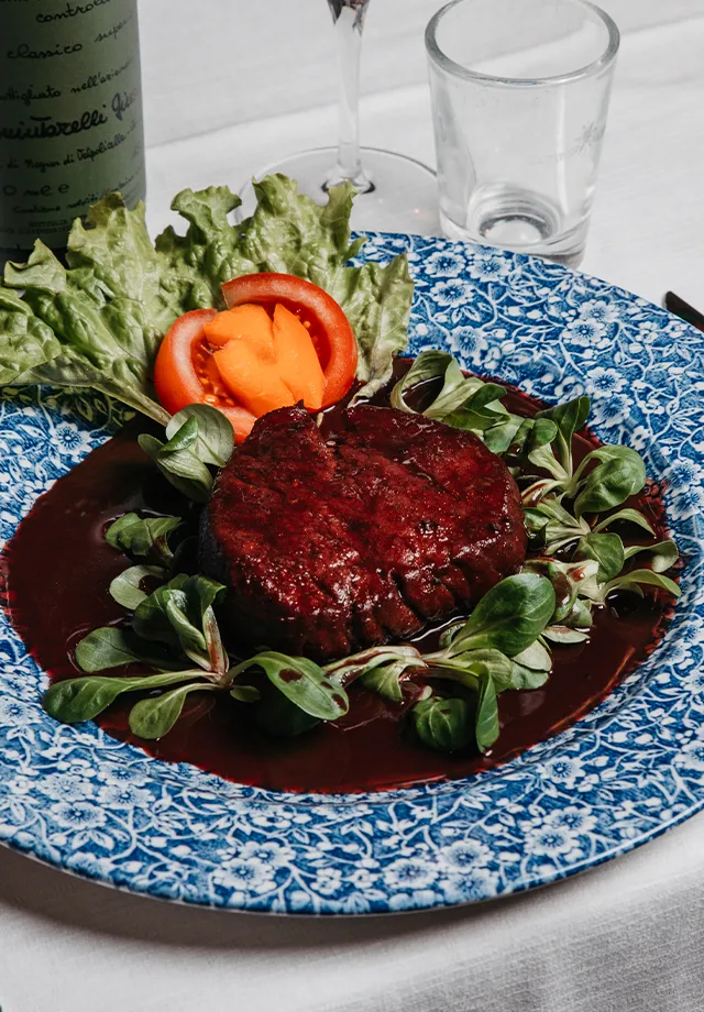 Cameriere serve un filetto di scottona all'Amarone con verdure fresche