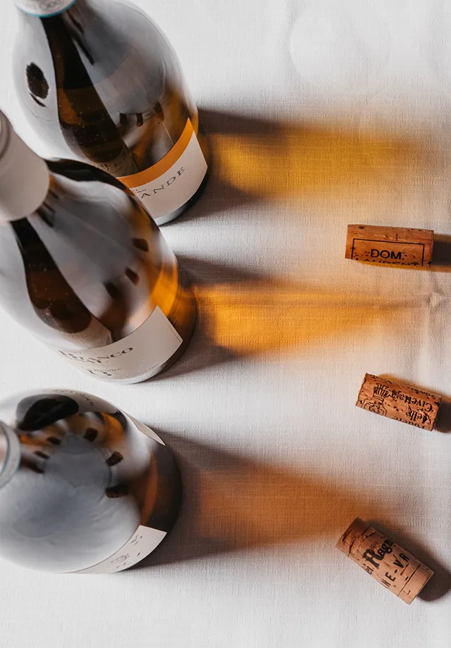 Tre bottiglie di vino riprese dall'alto con a lato i tappi in sughero